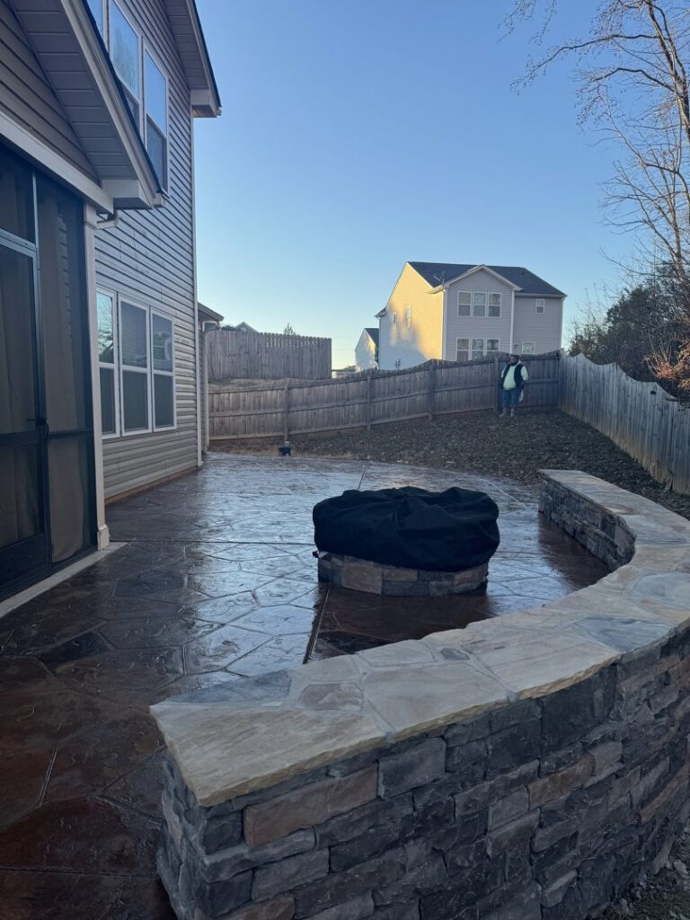A custom stamped concrete patio featuring a built-in fire pit and seating wall, created by Rodriguez Concrete Creations in Rock Hill, SC.
