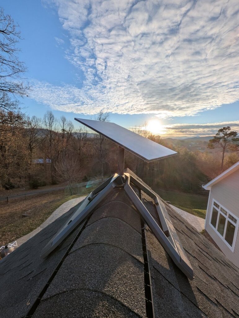 A Starlink satellite dish installed on a roof with vibrant autumn trees in the background by WX2 Tech in Asheville, NC.