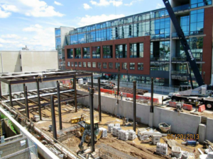 A multi-story building under construction with steel framing and a crane by Mega Construction in Philadelphia, PA.