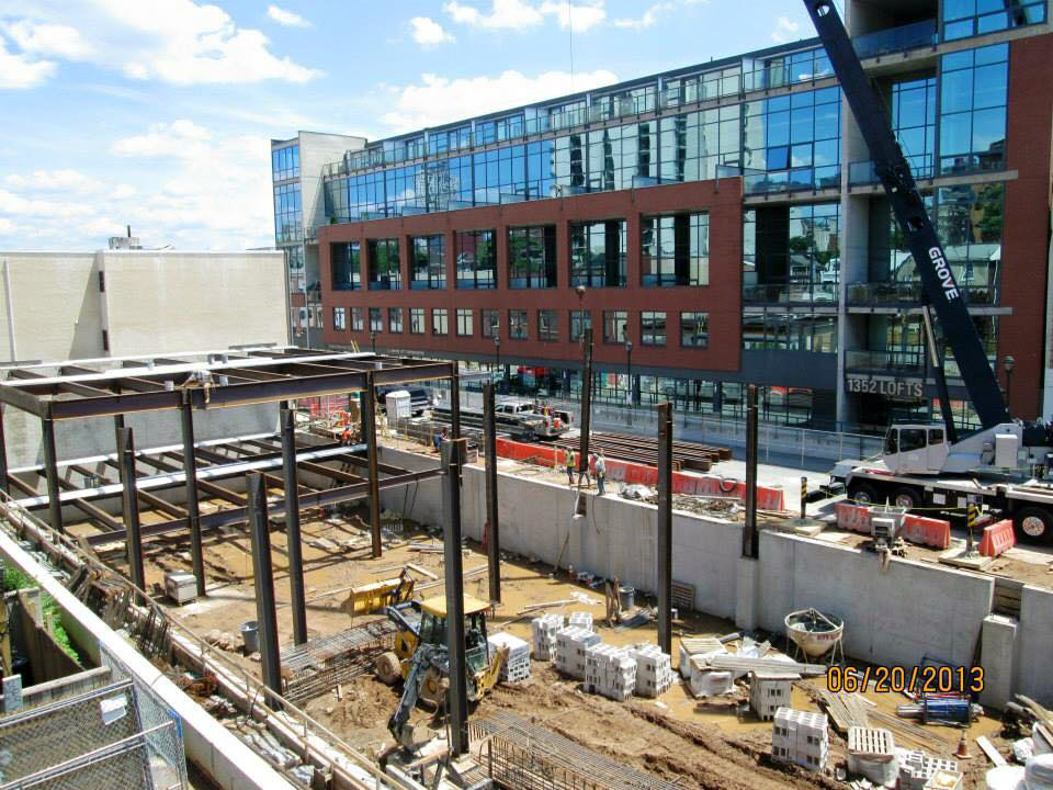A multi-story building under construction with steel framing and a crane by Mega Construction in Philadelphia, PA.