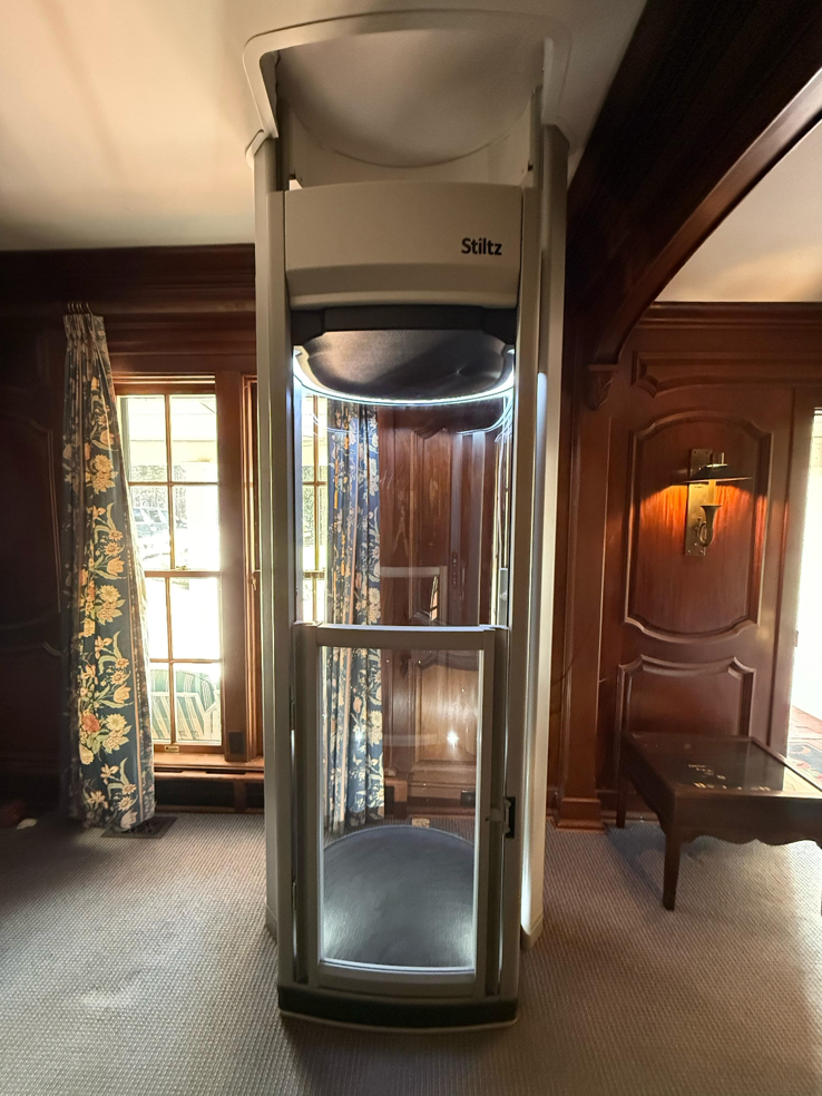 A Stiltz home lift expertly installed by Stiltz of Charlotte Raleigh Greenville in a wood-paneled room in Concord, NC.