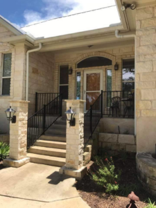 A stone facade home entrance featuring new black metal railings by Whitehorn Construction in Austin, TX.