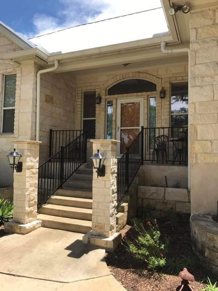 A stone facade home entrance featuring new black metal railings by Whitehorn Construction in Austin, TX.