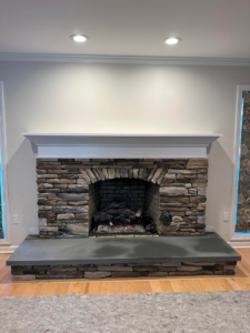 A newly installed stone fireplace with a white mantel by Tomori's masonry llc in Cheshire, CT