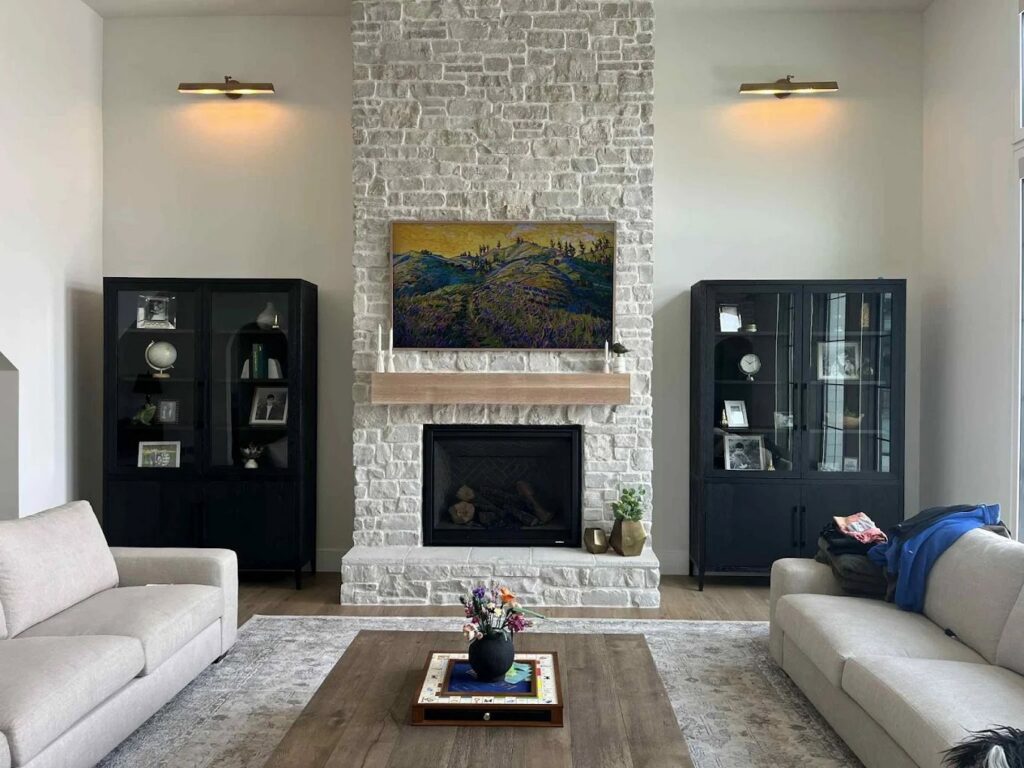 A beautiful stone fireplace with a wooden mantel and custom built-in cabinets by Renegade Woodworks in Kearney, NE.