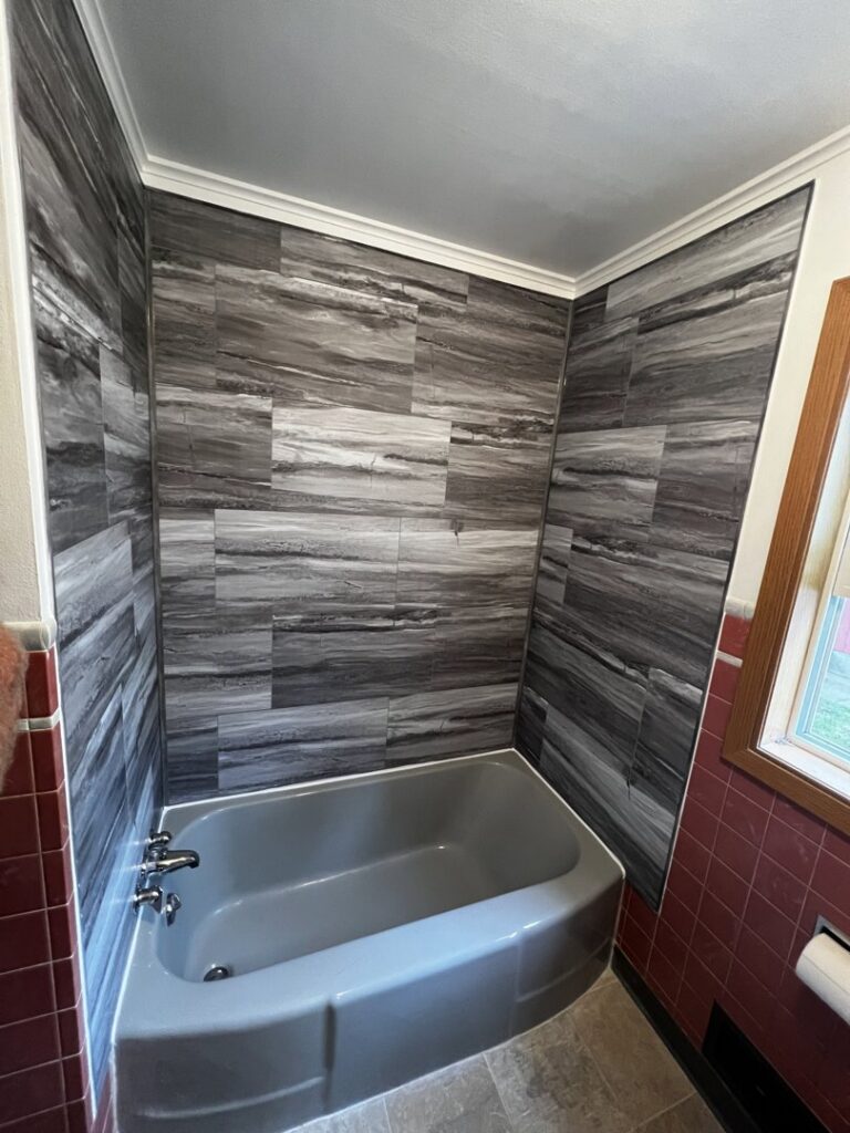 A custom stone fireplace with a mounted television and wooden mantel, built by ROTH WORX LLC in Bismarck, ND.