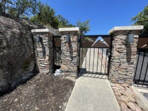 Newly constructed stone pillars with decorative metal gates at an entrance by R and R contractors in Rogers, AR.