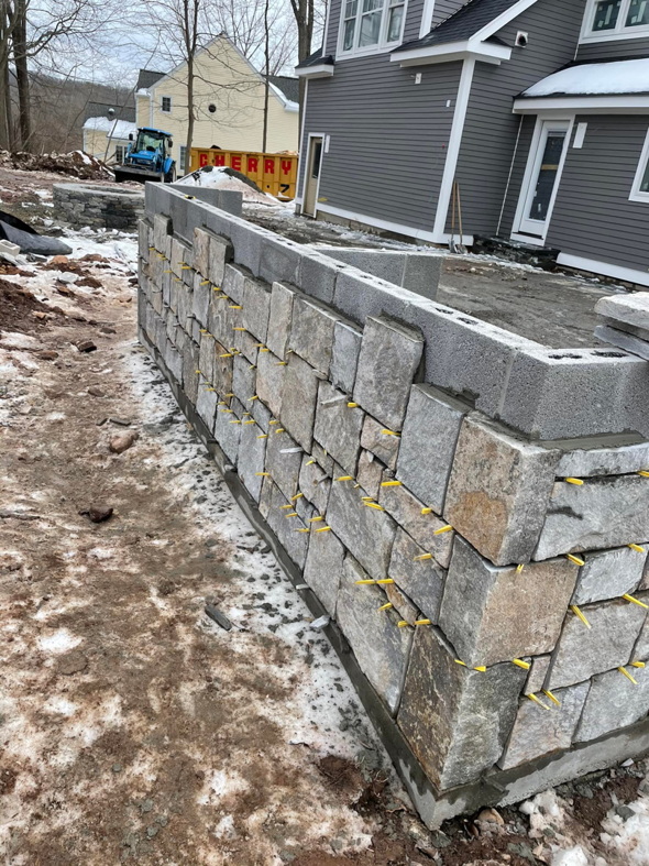 A stone retaining wall under construction by Tomori's masonry llc in Cheshire, CT