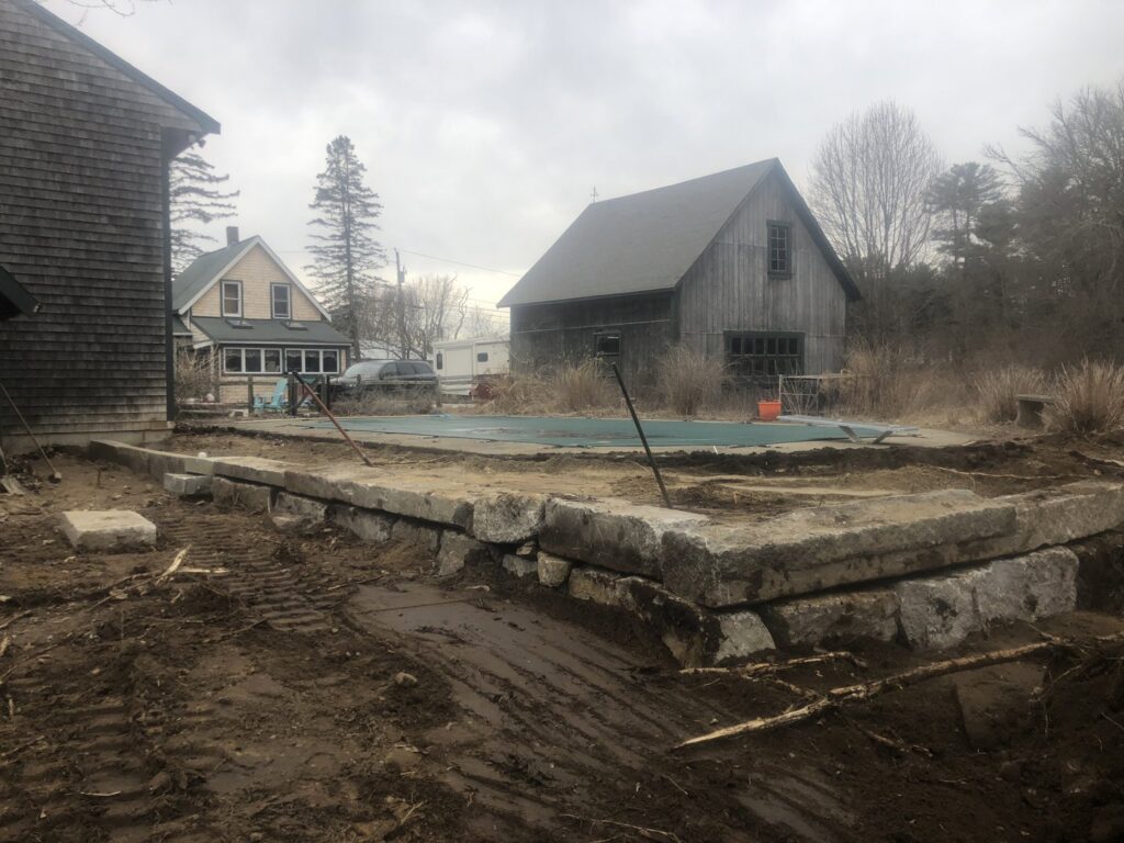 A large stone retaining wall constructed around a pool area by Solimini Excavation and Utility in Freetown, MA