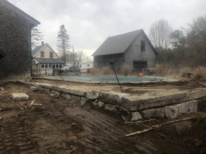 A large stone retaining wall constructed around a pool area by Solimini Excavation and Utility in Freetown, MA