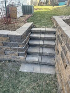 Newly installed or repaired stone steps and a retaining wall in a backyard by K-Way's Handyman Services in Lincoln, NE