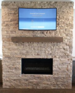A modern fireplace with stone veneer and a mounted television above, completed by Boise Handyman & Remodel in Boise, ID.