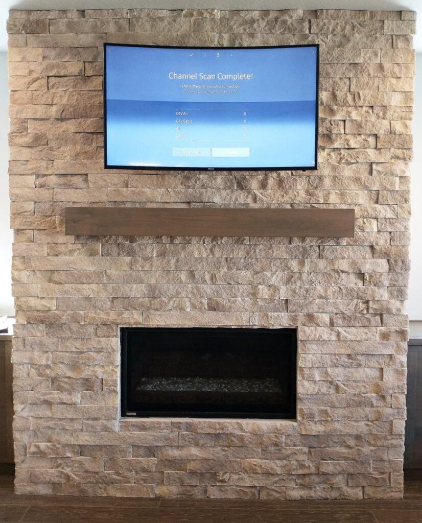 A modern fireplace with stone veneer and a mounted television above, completed by Boise Handyman & Remodel in Boise, ID.