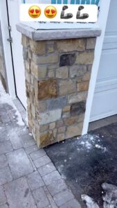 A newly installed stone veneer pillar next to a garage door by L12 Construction LLC in Oshkosh, WI.