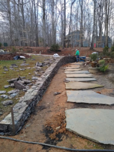 A stone wall and flagstone pathway under construction by Camacho's Construction in Durham, NC