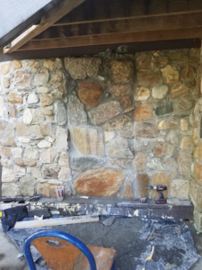 A stone wall restoration project in progress with tools and materials at Stone cutter masonry restoration & waterproofing in Georgetown, KY.