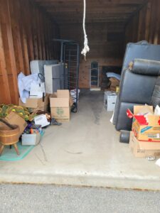 A storage unit filled with furniture, mattresses, and boxes, indicating a cleanout job by Primetime Hauling and Junk Removal in Spokane, WA.