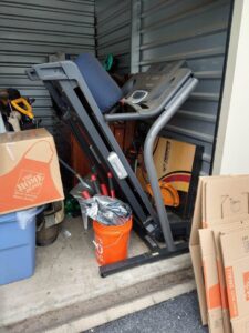 A storage unit packed with a treadmill, boxes, and other items for cleanout by Junk Runner, LLC in East Berlin, PA.