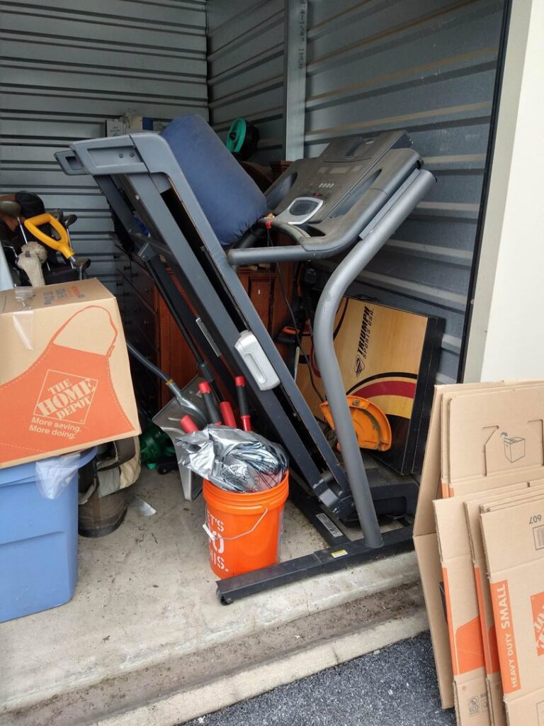 A storage unit packed with a treadmill, boxes, and other items for cleanout by Junk Runner, LLC in East Berlin, PA.