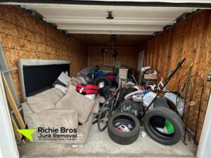 A storage unit packed full of a couch, bicycle, tires, and trash, ready for junk removal by Richie Bros Junk Removal in Urbandale, IA.