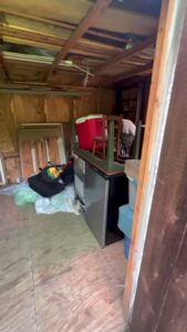 The interior of a cluttered storage unit or shed with items like a mini-fridge and coolers, ready for junk removal by City to City Junk Removal Fort Worth, TX.