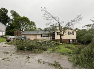 Extensive storm damage with fallen tree branches around a house, requiring cleanup by Elite Tree Service in Knoxville, TN.