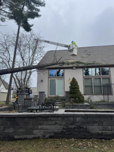 Scotts Tree Experts in Columbus, OH, performing storm damage tree removal with a worker in a bucket lift near a house.