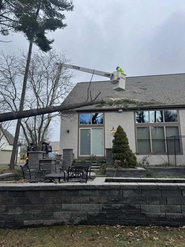 Scotts Tree Experts in Columbus, OH, performing storm damage tree removal with a worker in a bucket lift near a house.