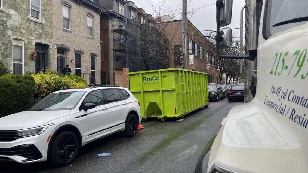 A green Broco Waste & Recycling dumpster placed on a residential street in Warminster, PA.