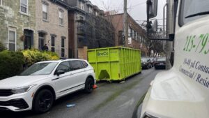 A green Broco Waste & Recycling dumpster placed on a residential street in Warminster, PA.