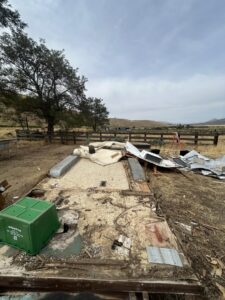 The remains of a demolished structure with insulation and debris scattered on the ground in a rural setting, ready for cleanout by Reno Junk Pros in Reno, NV.