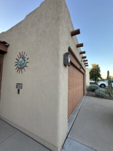 A finished stucco garage wall with a decorative sun emblem by Old Pueblo Stucco, Inc. in Tucson, AZ