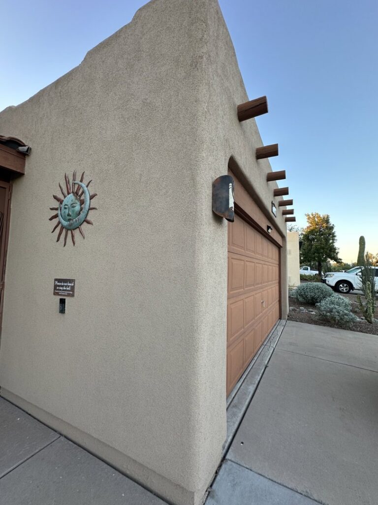 A finished stucco garage wall with a decorative sun emblem by Old Pueblo Stucco, Inc. in Tucson, AZ
