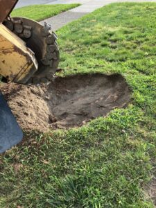 A stump grinder is actively working on removing a tree stump, creating wood chips for Magee Tree Service in Detroit, MI.