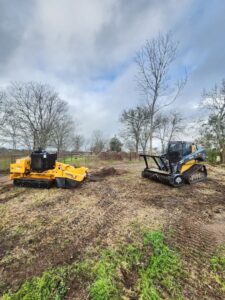 A stump grinder and other land clearing equipment on a job site, used by KIRI TREE service for tree work in Austin, TX.