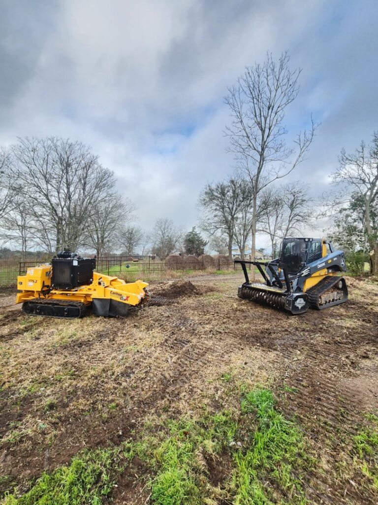 A stump grinder and other land clearing equipment on a job site, used by KIRI TREE service for tree work in Austin, TX.