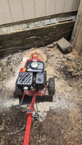 A red stump grinder machine actively working on a tree stump, demonstrating stump removal by Can Do Andrew in Gresham, OR.