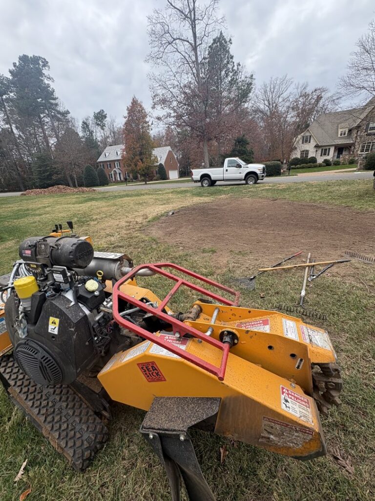 A yellow stump grinder positioned on a residential lawn, ready for or after stump removal by Ernesto tree service & landscaping LLC in Richmond, VA.