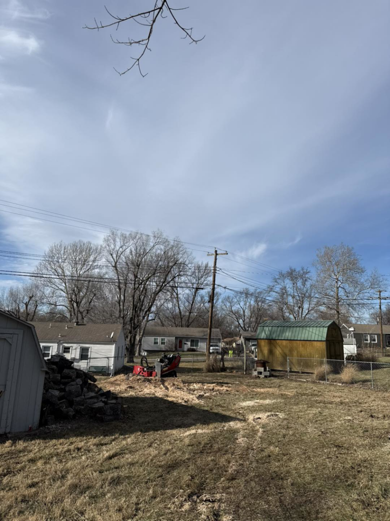 A stump grinder and wood chips in a backyard after tree removal service by Alpha & Omega in Lakehills, TX.