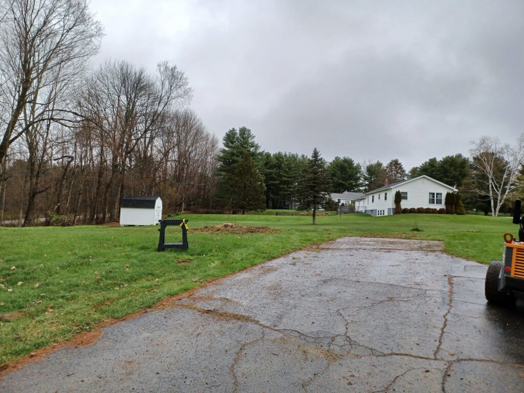 A tree stump and a piece of equipment in a residential yard, indicating stump grinding service by BlueWater Tree Service, LLC in Bangor, ME.