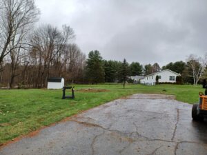 A tree stump and a piece of equipment in a residential yard, indicating stump grinding service by BlueWater Tree Service, LLC in Bangor, ME.