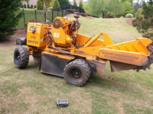 A Sharp Tree Service stump grinding machine on a residential lawn in Cumming, GA, performing stump removal.