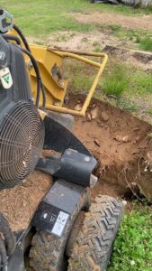 A stump grinder working on a large tree stump and roots for ED's Landscaping in Mechanicsville, VA.