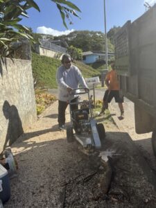 A worker operating a stump grinder to remove a tree stump, part of services by City Green Care Inc. in Honolulu, HI.