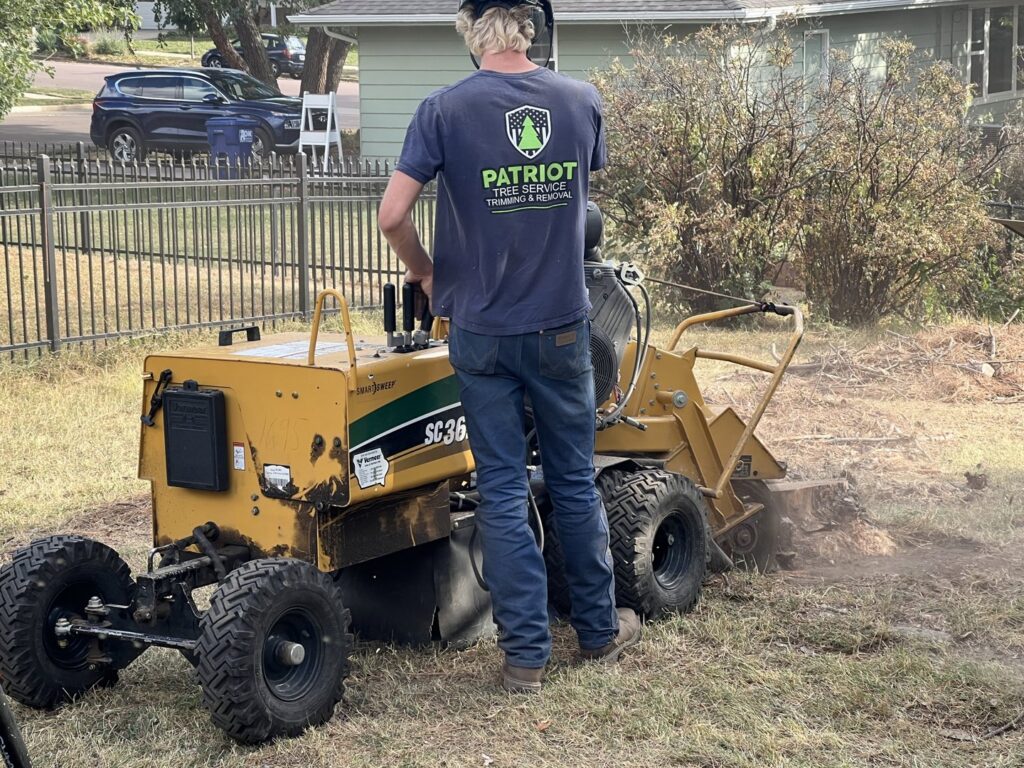 A Patriot Tree Service worker operating a stump grinder to remove a tree stump in Sioux Falls, SD