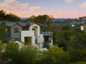 A stunning modern house exterior featuring stone and vertical siding, nestled on a hillside by Stone Acorn Builders in Bellaire, TX.