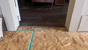 A close-up view of subflooring transitioning to finished wood flooring, showing interior work by HW Handyman Services in Springfield, MO.
