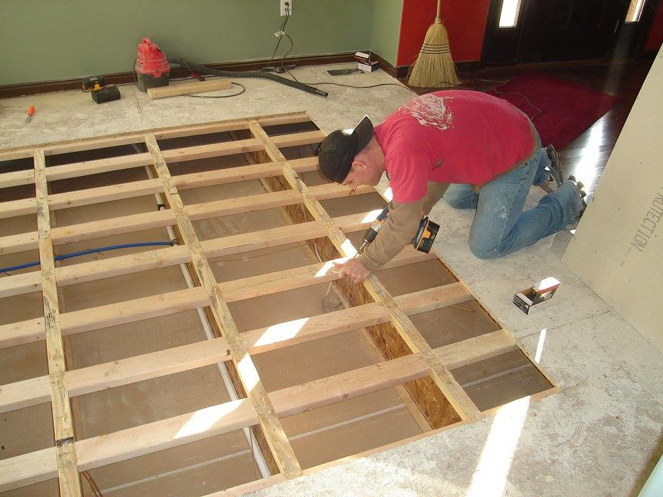 A handyman installing subfloor framing with a drill, demonstrating carpentry services by Honeycomb Handyman Services in Salt Lake City, UT.