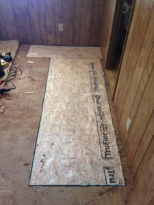 Subfloor being installed in a room with wood paneling, part of a remodeling project by AON Construction and Remodeling LLC in Wichita, KS.