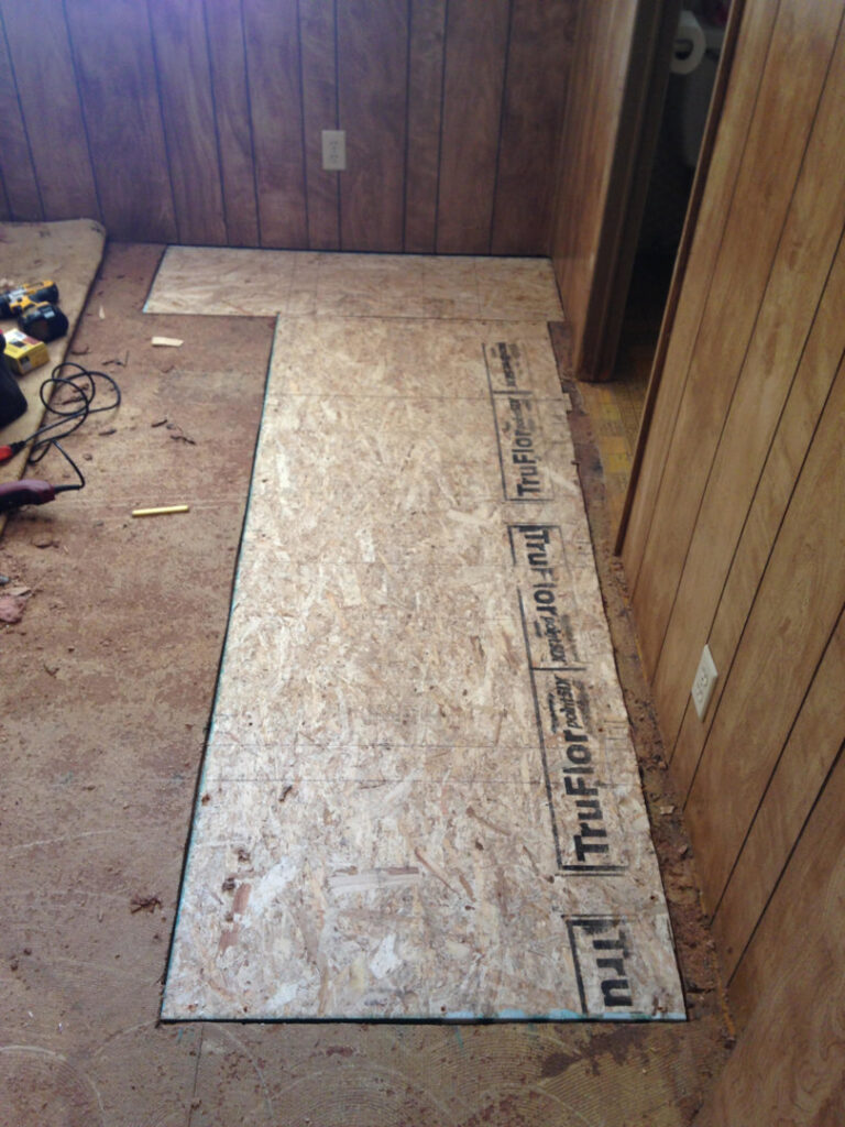 Subfloor being installed in a room with wood paneling, part of a remodeling project by AON Construction and Remodeling LLC in Wichita, KS.